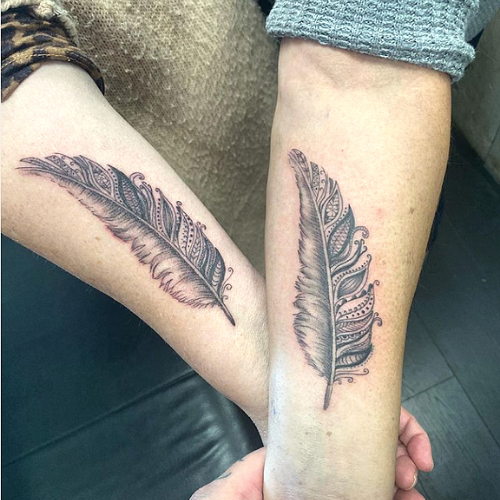 twin flame tattoos of feathers on forearm