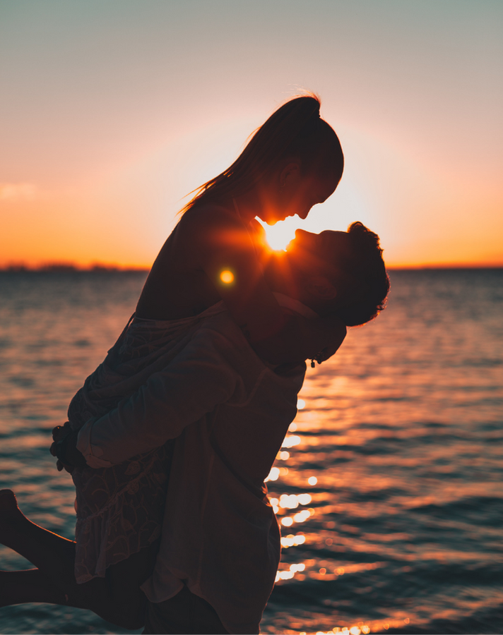 man carrying his woman in front of sunset