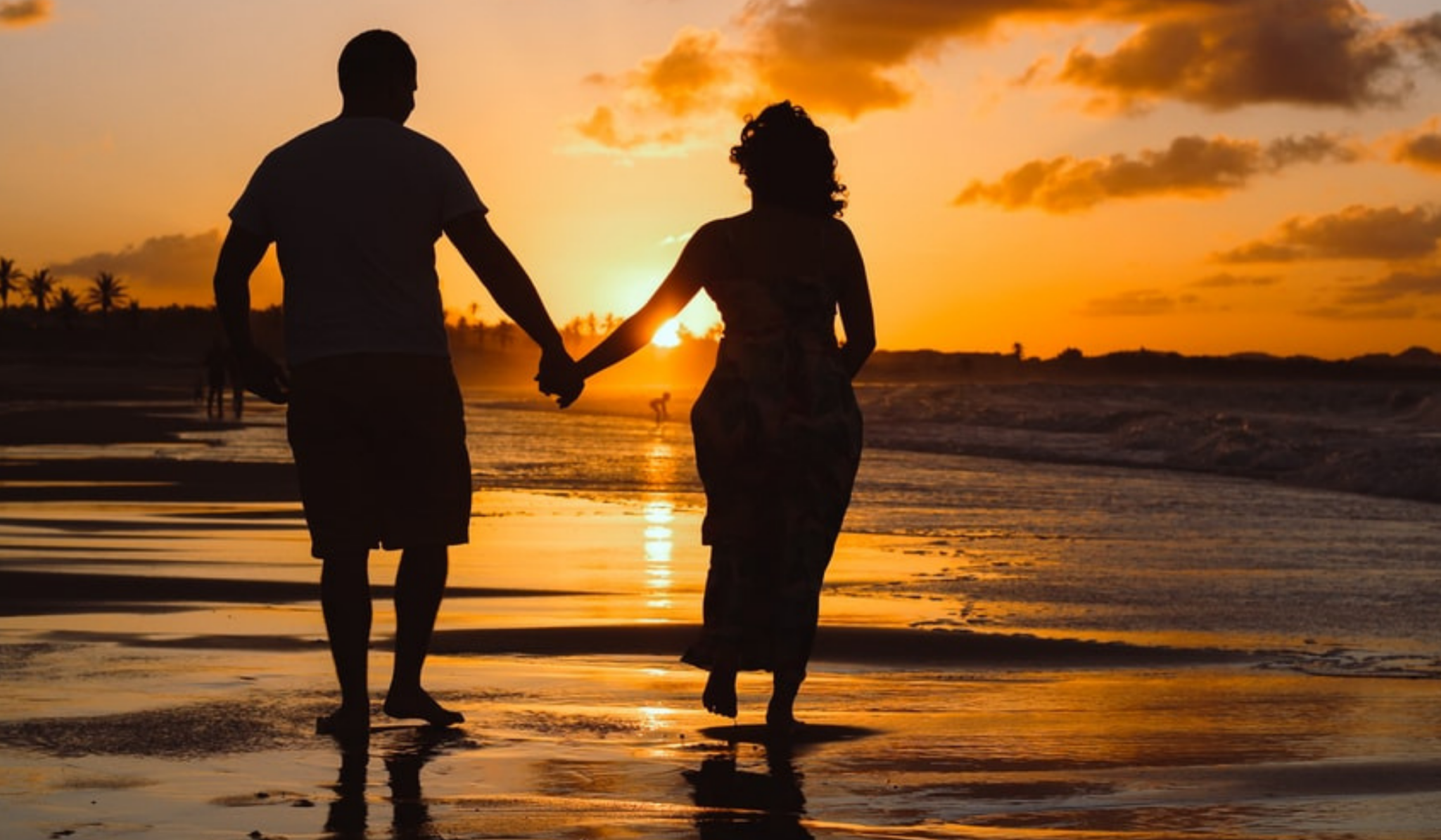 couple walking on the beach at sunset