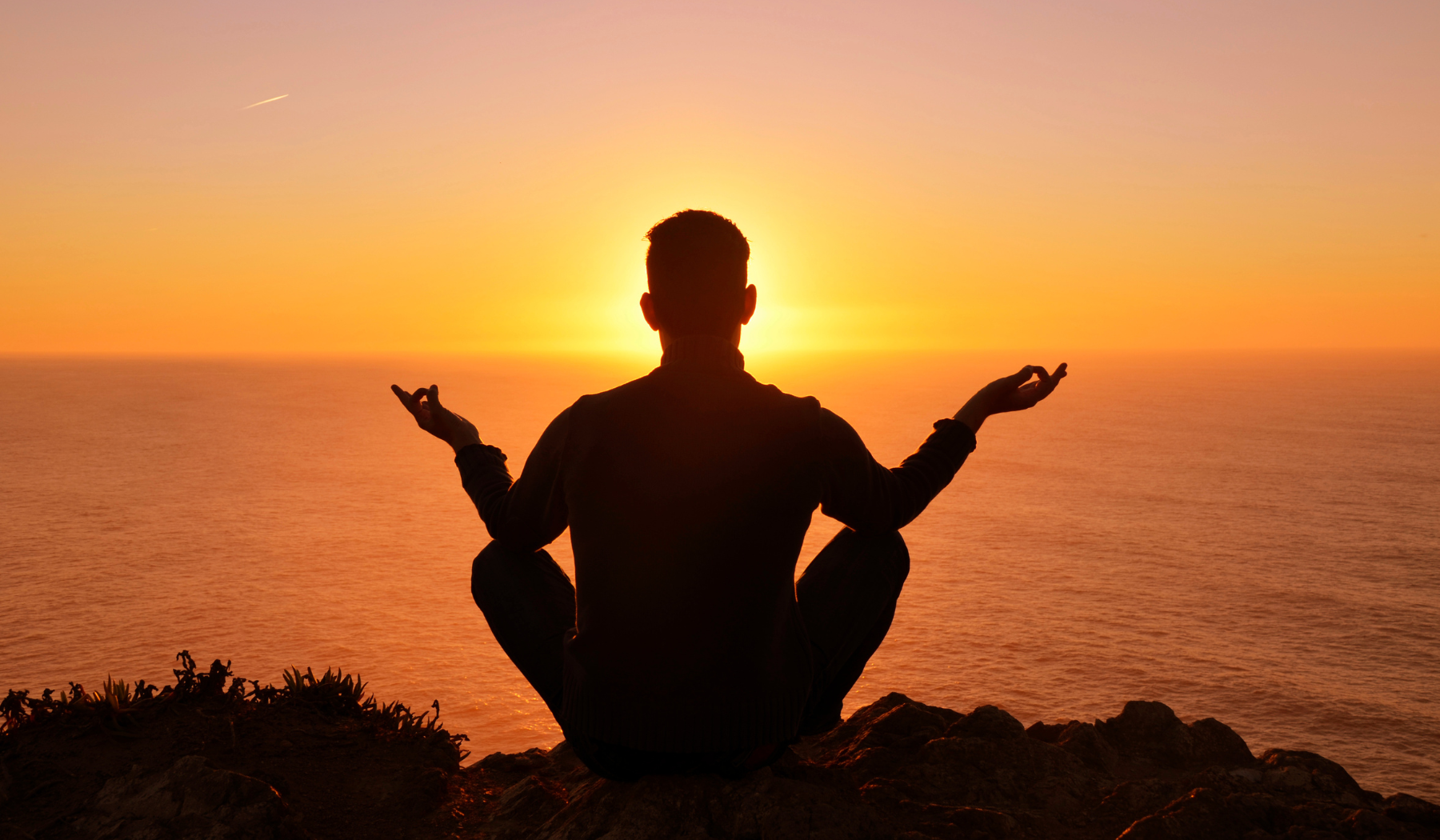 man meditating in front of the sun